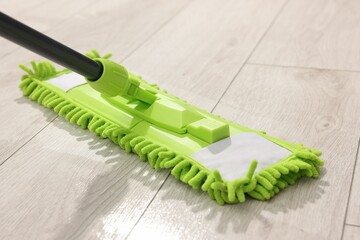 Microfiber mop on wooden floor, closeup. Cleaning equipment