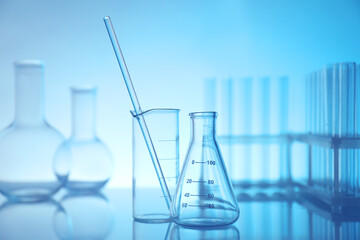 Laboratory glassware on mirror surface against light blue background