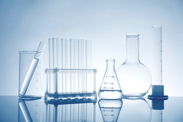 Laboratory glassware with liquid on mirror surface against light background