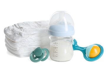 Feeding bottle with milk, diapers, baby rattle and pacifier isolated on white