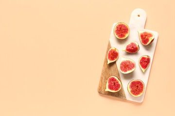 Wooden board with slices of ripe fresh figs on orange background