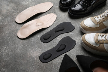 Set of stylish female shoes and orthopedic insoles on grunge background