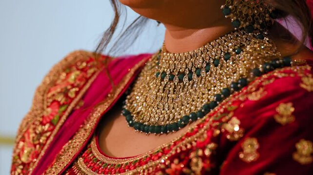 The bride is dressed in traditional red Indian clothes with beautiful neckless on her neck , Elements of Hindu wedding. Close up view.