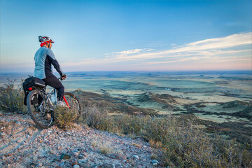Fototapeta premium senior male on a mountain bike contemplating a view of rolling prairie at dusk, Soapstone Prairie Natural Area near Fort Collins, Colorado