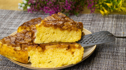 Delicious apple upside-down cake served on a rustic plate adorned with vibrant flowers and a cozy kitchen atmosphere