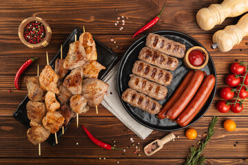 Grilled meat kebab and sausages on a wooden background with cherry tomatoes and spices. Barbecue Season