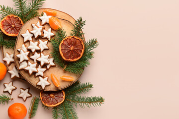 Wooden board of star-shaped gingerbread cookies with mandarin, dried orange and fir branches on beige background