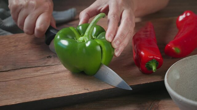 cook cut fresh green pepper on wooden kitchen board and removes the seeds. food closeup, process of making gazpacho soup