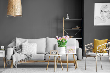 Interior of living room with gift box and tulips for International Women's Day on tables
