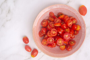 sliced cherry tomatoes in pink ceramic bowl.