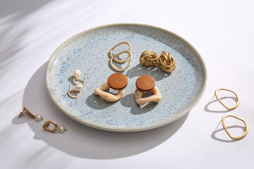 Plate with beautiful earrings on white background