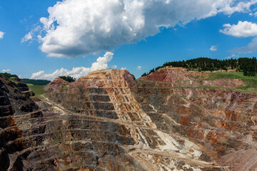 Open-Pit Gold Mine Landscape Under a Blue Sky with Clouds