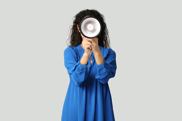 Obraz premium Young African-American woman with megaphone on light background