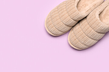Pair of beige soft slippers on lilac background. Top view
