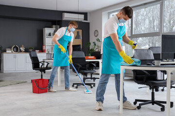 Male workers of cleaning service disinfecting in office