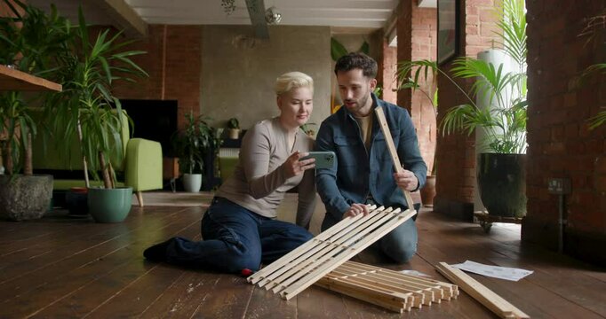 Couple looking at instructions Together on a Phone to build a flat pack