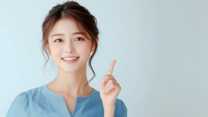笑顔で上を指差す若い女性。注目、案内、視線誘導に最適な人物素材。