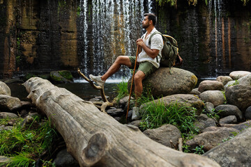 Hiker resting in front of a natural waterfall