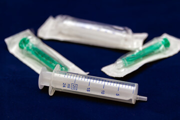 Sterile syringes and packaged needles on a dark blue background, used for medical treatments,...