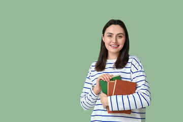 Young woman holding books on green background
