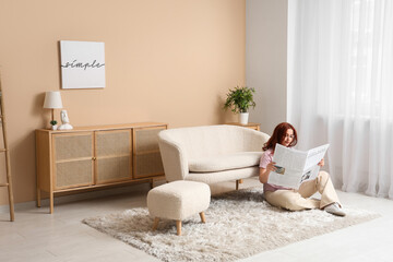 Young woman reading newspaper on carpet at home