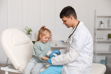 Obraz premium Male pediatrician measuring temperature of little girl with infrared thermometer in clinic