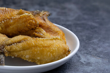 Deliciously crispy fried fish served on a white plate against a dark surface in a cozy setting