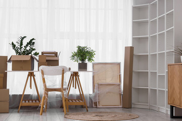 Furniture, houseplants and cardboard boxes with belongings in new apartment. Moving house concept