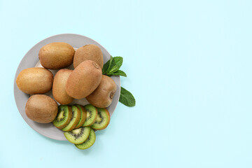 Plate with fresh kiwi and mint on blue background