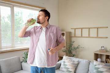 Young man drinking cucumber water at home