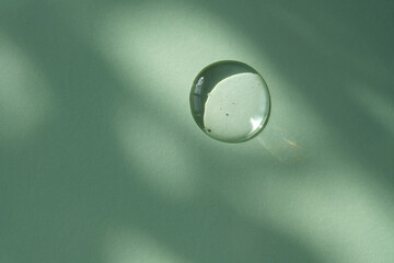 A drop of micellar water on a green background.