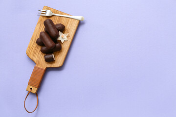 Wooden board with tasty chocolate glazed curd snacks with vanilla flavor on lilac background