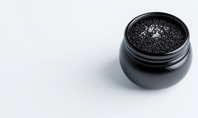 Elegant black container filled with fine black granules showcasing a luxurious texture on a soft white background, perfect for culinary or artistic use
