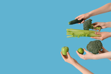 Hands holding green vegetables and fruits on blue background
