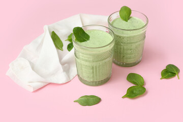 Glasses of fresh spinach smoothie on pink background
