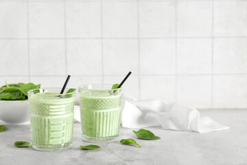 Glasses of fresh spinach smoothie on white table