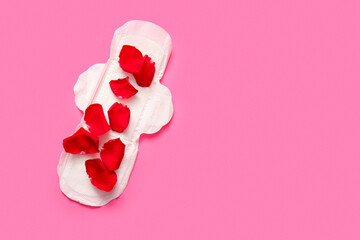 Menstrual pad with rose petals on pink background