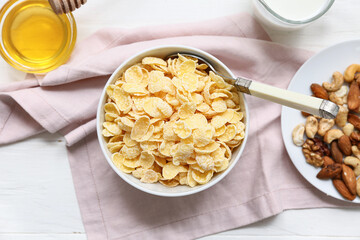 Napkin and bowl with cornflakes on white wooden background, closeup