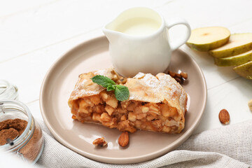 Plate with piece of tasty pear strudel, cut fresh fruit and milk on white wooden background
