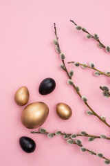 Golden and black eggs with willow twigs on tender pink background, easter celebration concept decoration