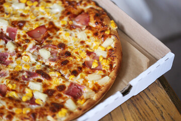 Hawaiian pizza background. Ham and pineapple pizza pie. Takeaway box container. Freshly baked cheesy pizza for delivery. Classic fast food meal with a crispy crust and delicious toppings.