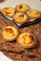 Portugal's traditional sweet dessert Pastel de nata egg custard tart pastry in cup close up on wooden background