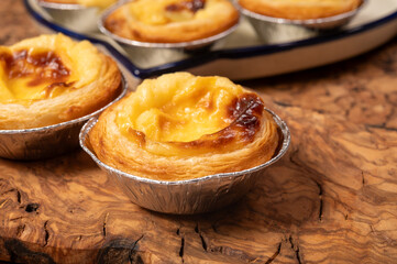 Portugal's traditional sweet dessert Pastel de nata egg custard tart pastry in cup close up on wooden background