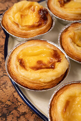 Portugal's traditional sweet dessert Pastel de nata egg custard tart pastry in cup close up on wooden background
