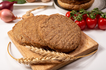 Round vegetarian patties or burgers made from grains, vital wheat gluten food, uncooked and grilled