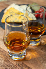 Whiskey and cheese pairing, tasting whisky glasses and plate with sliced crumbly old blue stilton and blue shropshire cheeses, Great Britain food and drink