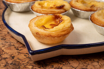 Portugal's traditional sweet dessert Pastel de nata egg custard tart pastry in cup close up on wooden background