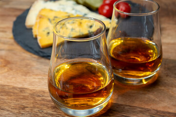 Whiskey and cheese pairing, tasting whisky glasses and plate with sliced crumbly old blue stilton and blue shropshire cheeses, Great Britain food and drink