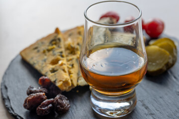 Whiskey and cheese pairing, tasting whisky glass and plate with sliced blue stilton and blue shropshire cheeses, Great Britain food and drink