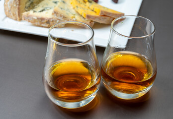 Whiskey and cheese pairing, tasting speyside whisky glasses and plate with sliced cheddar, blue stilton and blue shropshire cheeses, Great Britain food and drink